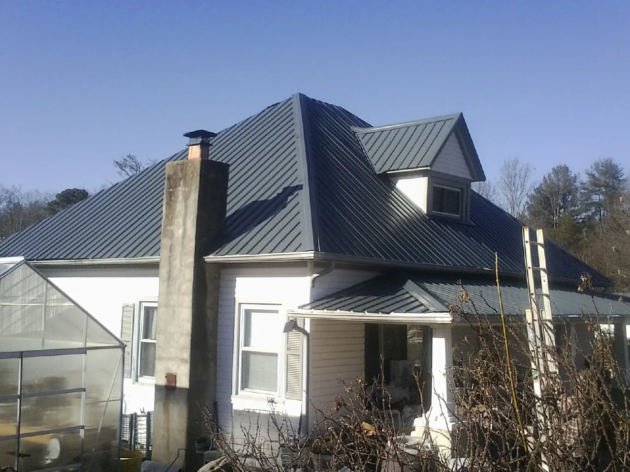Dark blue standing seam metal roof on a white farmhouse with dormer — Slate & Tile Roof Repair by Roofing Brothers in Sonora