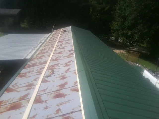 Old rusted panels beside newly installed green metal roofing — Wind Damage Roof Repair by Roofing Brothers in Sonora