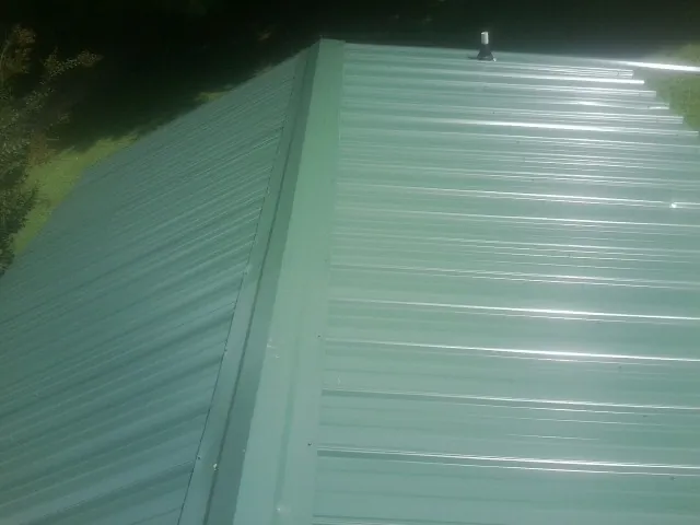 New green metal panels meeting at the ridge of a roof — Flat Roof Repair work by our crew in Sonora