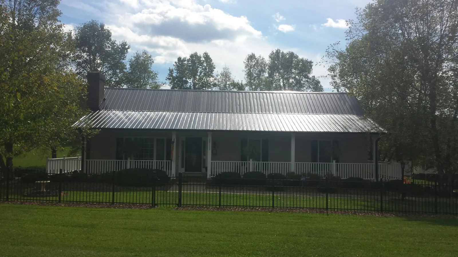 Gray metal roof on a brick ranch with a full width front porch — Gutter Guard Installation work by our crew in Sonora