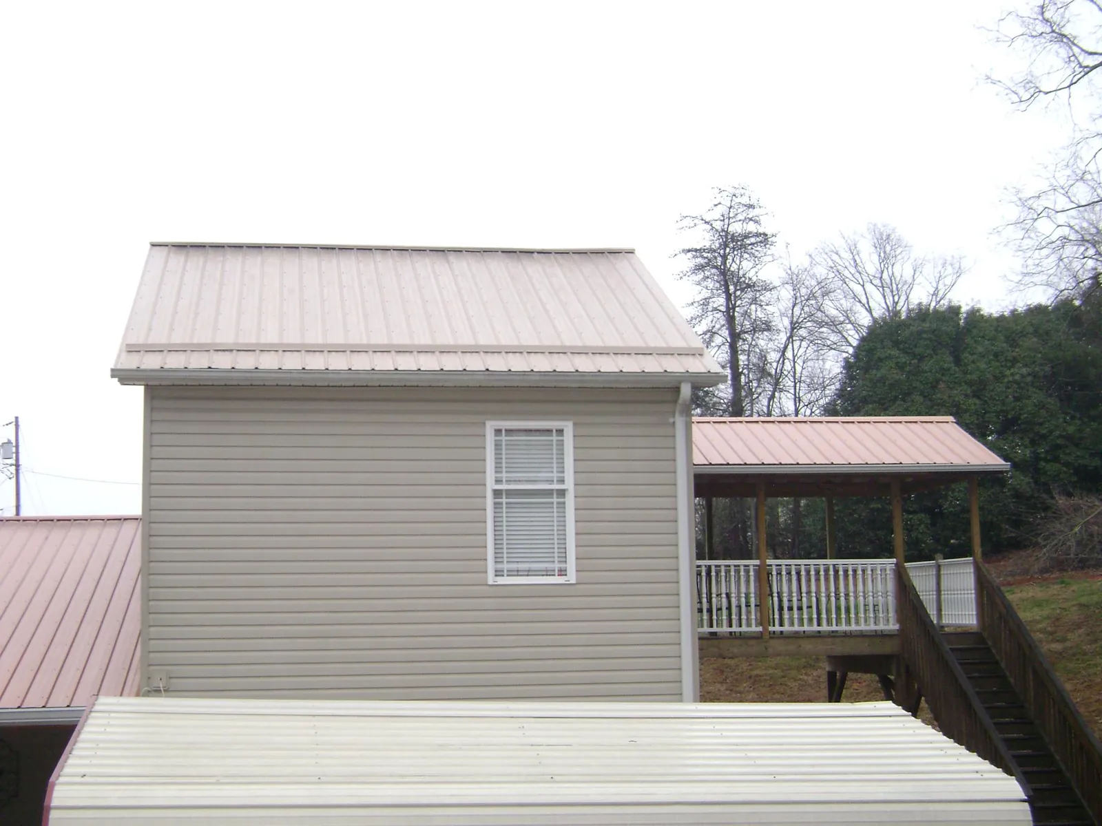Tan metal roofs on a two story addition and attached porch, from a Roof Replacement job in Sonora